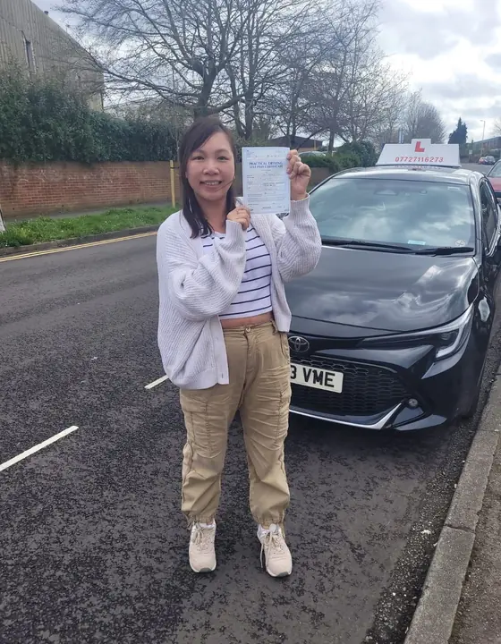 Student standing by a car after passing their test