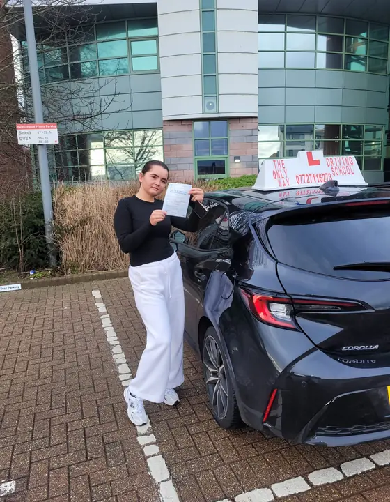 Student standing by the driving school car after passing