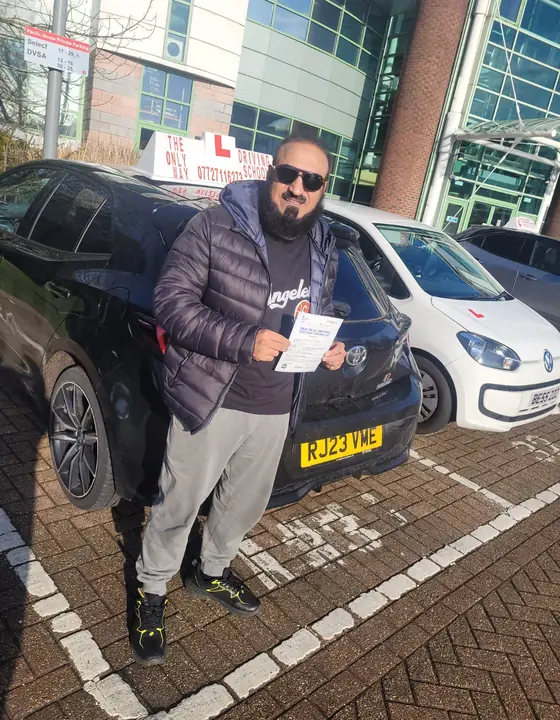 Student holding a pass certificate beside the tuition car