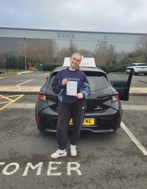 Student beside the driving school vehicle after passing
